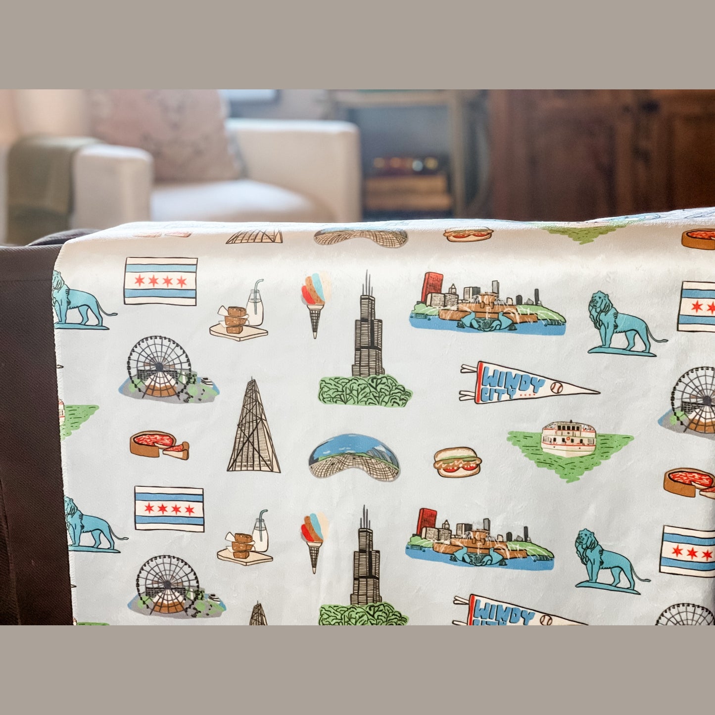 Cozy Chicago-themed plush throw blanket, 60x80 inches, featuring iconic city landmarks like deep dish, a Ferris wheel, lion, bean, a boat on a green river, Windy City flag, and other elements in vibrant colors.