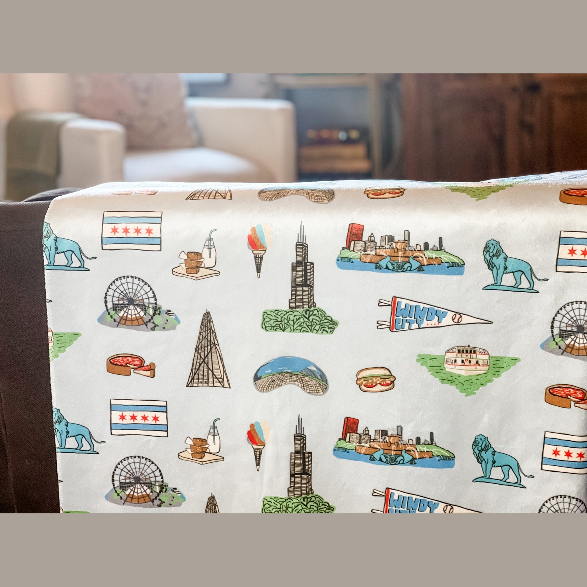 Cozy Chicago-themed plush throw blanket, 60x80 inches, featuring iconic city landmarks like deep dish, a Ferris wheel, lion, bean, a boat on a green river, Windy City flag, and other elements in vibrant colors.