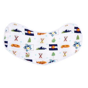 Baby wearing a white bib with colorful Colorado-themed illustrations, smiling on a soft, neutral background.