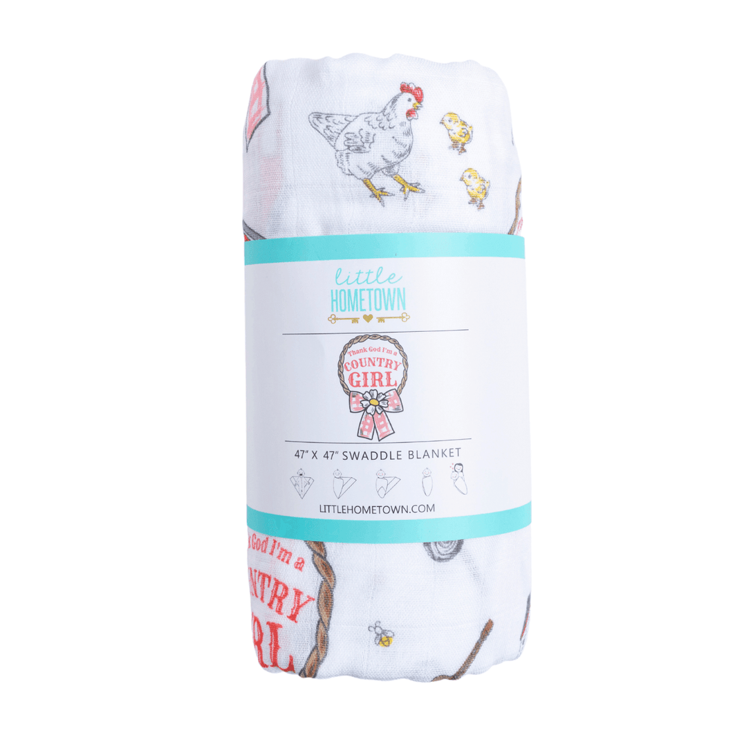 White muslin swaddle blanket with pink floral design and 