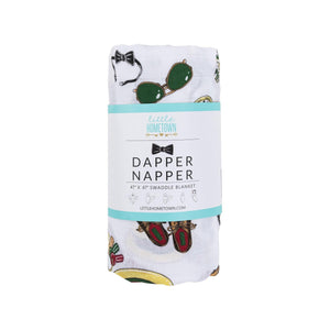 Baby swaddle blanket with a playful print of bow ties, mustaches, and glasses on a white muslin fabric.