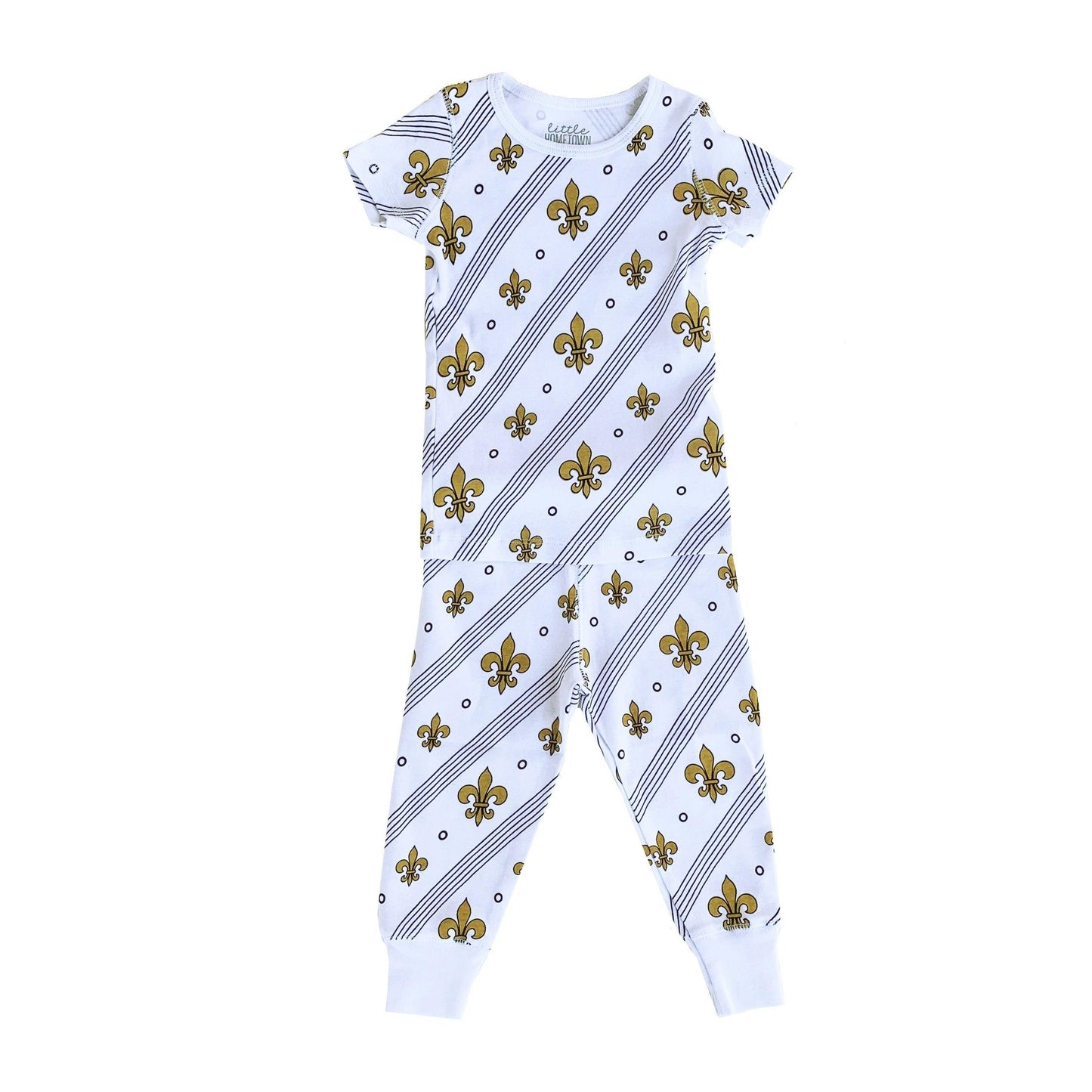 Toddler wearing white pajamas with blue fleur-de-lis pattern, smiling and holding a stuffed animal.