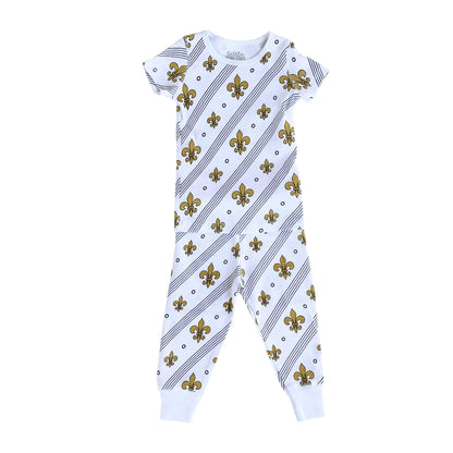 Toddler wearing white pajamas with blue fleur-de-lis pattern, standing on a white background.