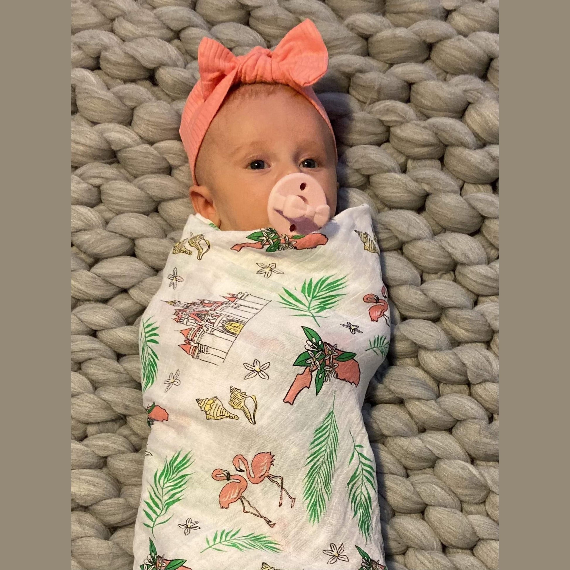 Soft muslin swaddle blanket with vibrant Florida-themed floral print, featuring pink hibiscus and green leaves.