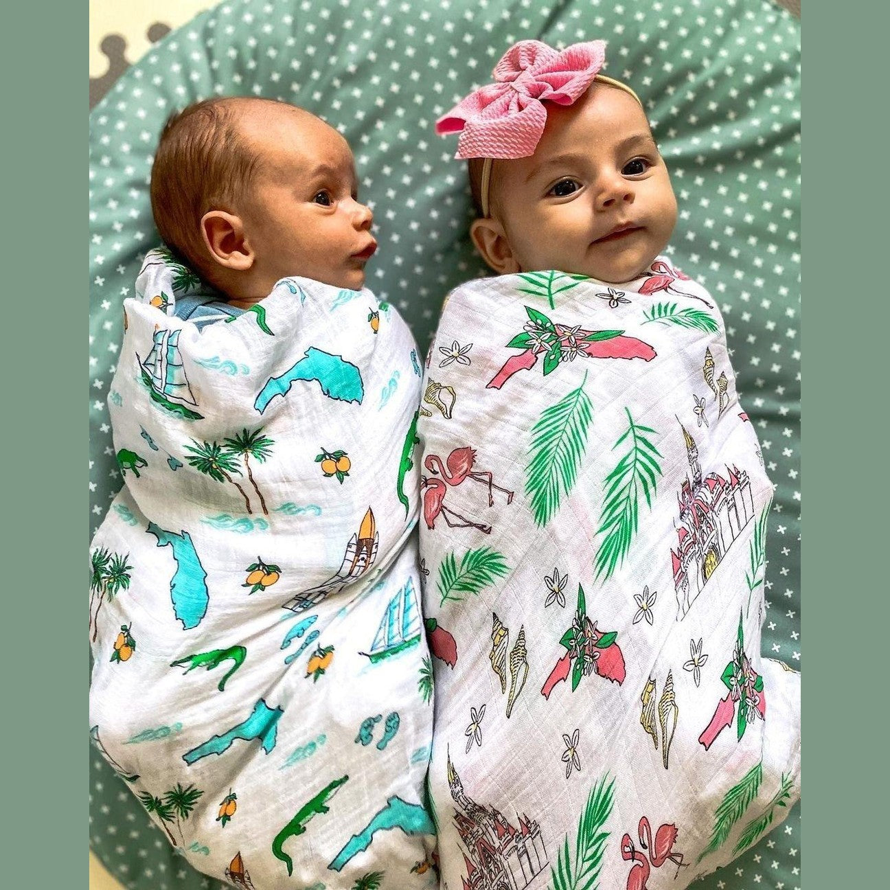 Soft muslin swaddle blanket with vibrant floral print, featuring pink, yellow, and green flowers on a white background.