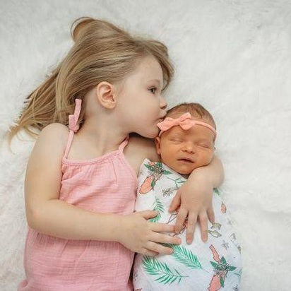 Soft muslin swaddle blanket with vibrant Florida-themed floral print, featuring pink hibiscus and green leaves.