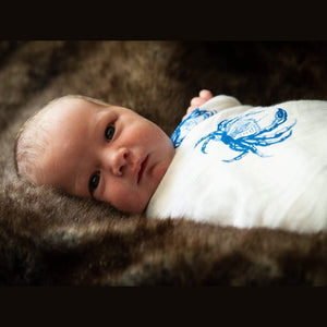 Blue crab-themed baby muslin swaddle blanket and burp cloth set, featuring playful crab illustrations on white fabric.