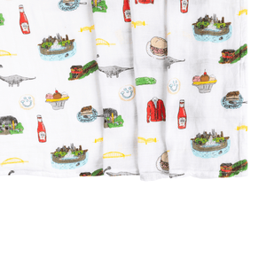 Pittsburgh-themed baby gift set with muslin swaddle blanket and burp cloth, featuring city icons and landmarks.
