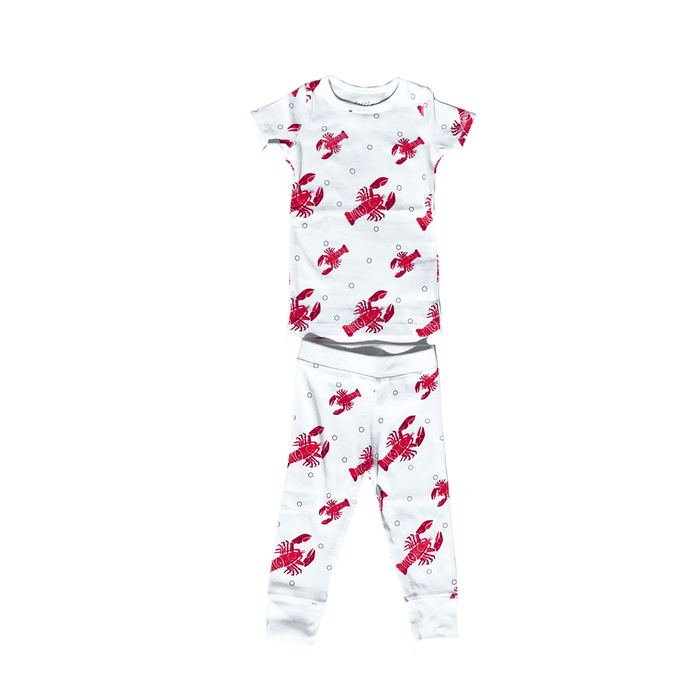 Toddler wearing white pajamas with red lobsters and crawfish, smiling and holding a toy lobster.