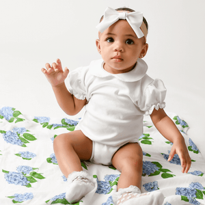 Soft white muslin swaddle blanket adorned with delicate blue and pink hydrangea flowers, perfect for newborns.