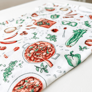 Toddler wearing colorful Jambalaya-themed pajamas with shrimp, sausage, and rice illustrations on a white background.