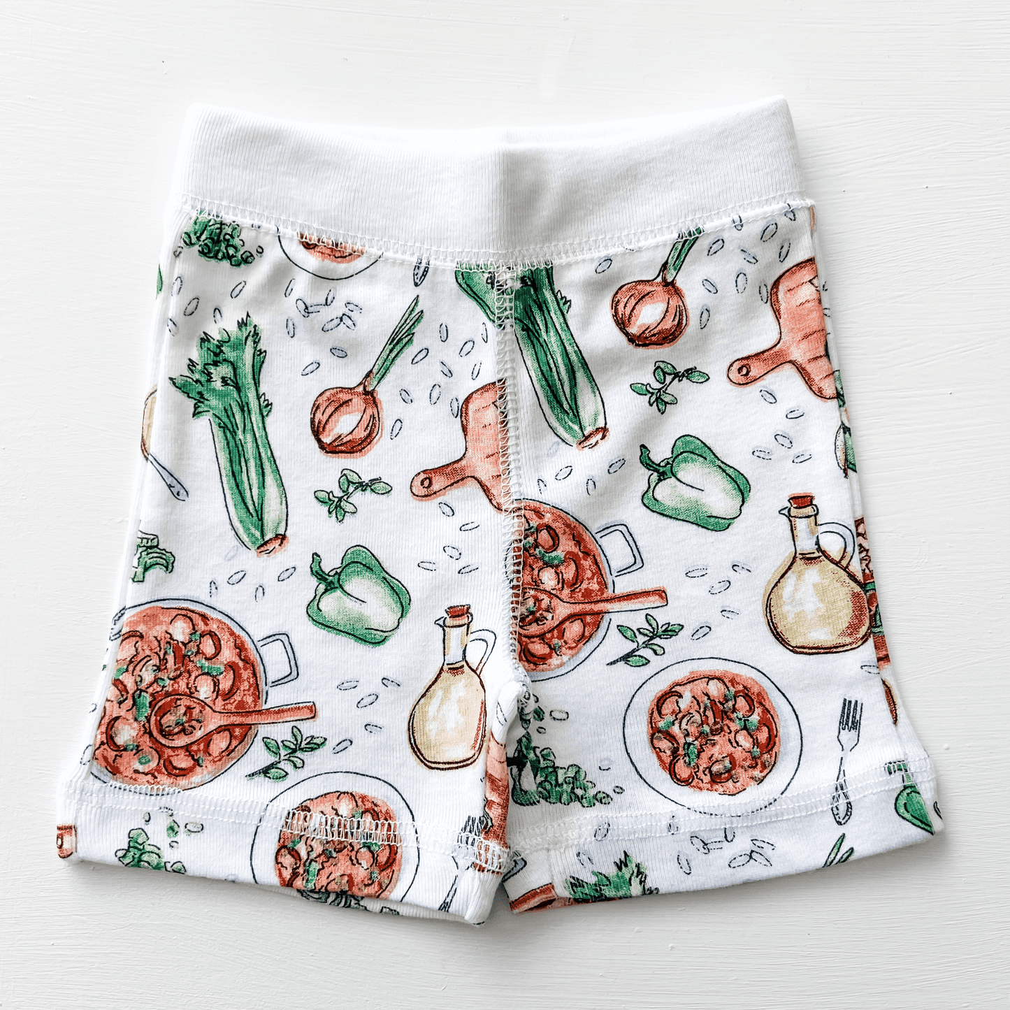 Toddler wearing white pajamas with colorful Louisiana-themed illustrations, including crawfish and alligators.
