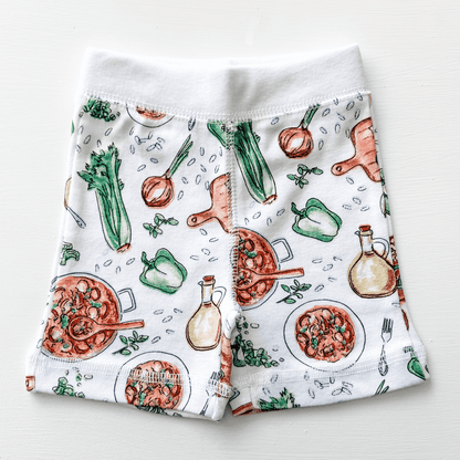 Toddler wearing white pajamas with colorful Louisiana-themed illustrations, including crawfish and alligators.