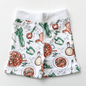 Toddler wearing white pajamas with colorful Louisiana-themed illustrations, including crawfish and alligators.