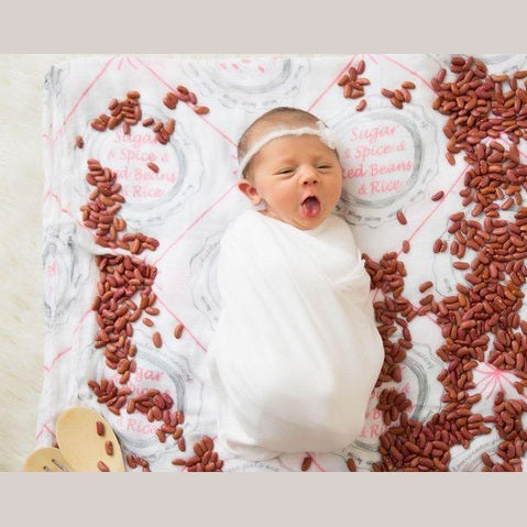 Louisiana-themed baby girl muslin swaddle blanket with pink and white design, featuring state icons and landmarks.