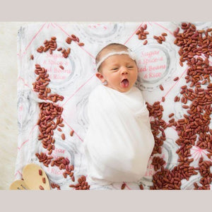 Louisiana-themed baby girl muslin swaddle blanket with pink and white design, featuring state icons and landmarks.