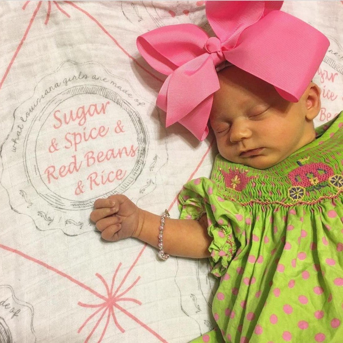 Louisiana-themed baby girl muslin swaddle blanket with pink accents, featuring state icons and "Louisiana" text.