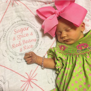 Louisiana-themed baby girl muslin swaddle blanket with pink accents, featuring state icons and "Louisiana" text.