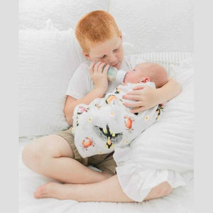 White muslin swaddle blanket with Maryland-themed illustrations, including crabs, lighthouses, and state symbols.