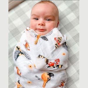 White muslin baby swaddle blanket with Maryland-themed illustrations, including crabs, lighthouses, and state symbols.