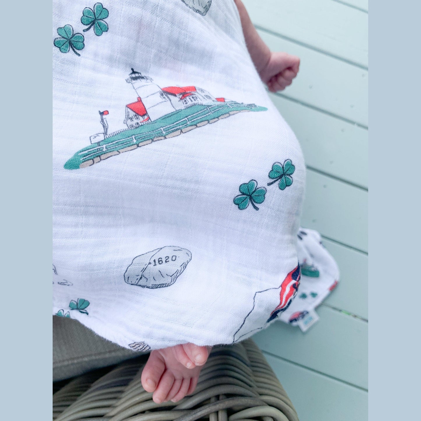 Massachusetts-themed baby muslin swaddle blanket with state icons and landmarks in soft pastel colors.