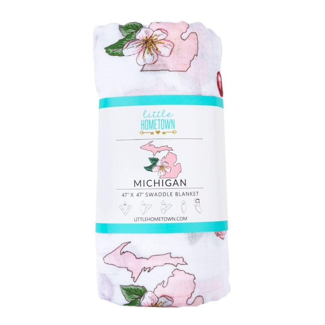 White muslin swaddle blanket with colorful floral patterns and 