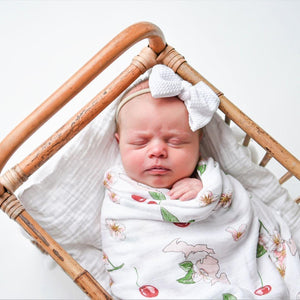 White muslin swaddle blanket with colorful floral patterns and "Michigan" text, laid flat on a white background.