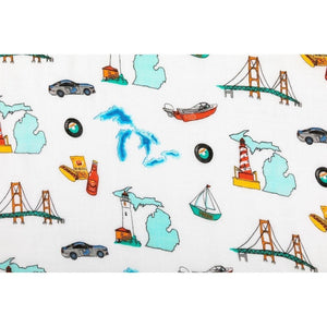 White muslin swaddle blanket with blue and yellow Michigan-themed illustrations, including the state outline and landmarks.