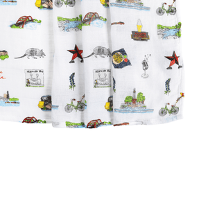 White muslin swaddle blanket with colorful Austin-themed illustrations, including landmarks, cacti, and guitars.