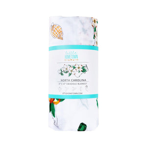 North Carolina-themed baby muslin swaddle blanket with floral design, featuring state symbols and landmarks.