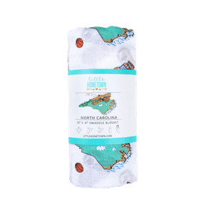 North Carolina-themed baby muslin swaddle blanket with state icons like lighthouses, cardinals, and dogwood flowers.