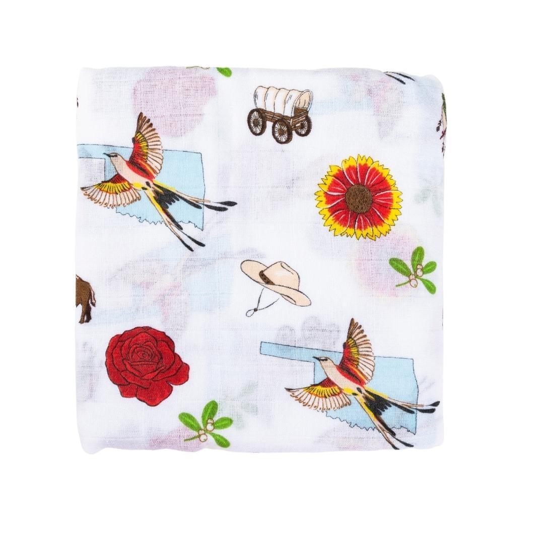 Baby swaddle blanket with Oklahoma map design, featuring landmarks, animals, and state symbols in soft pastel colors.