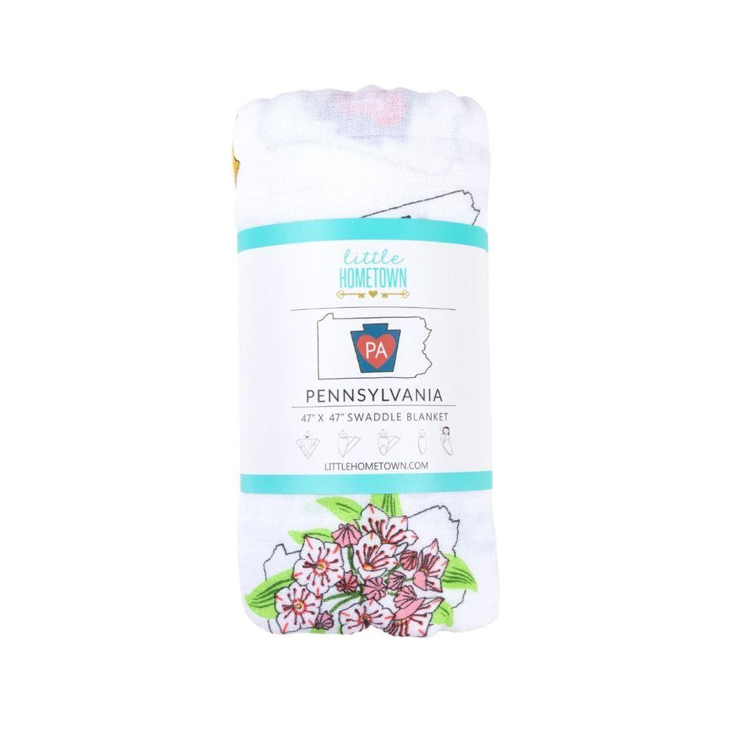 Pennsylvania-themed baby muslin swaddle blanket with state icons like the Liberty Bell, deer, and barns on white fabric.