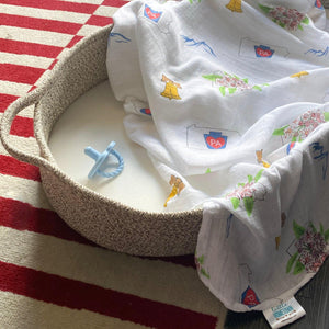 White muslin swaddle blanket with Pennsylvania state icons, including Liberty Bell, covered bridge, and state flower.