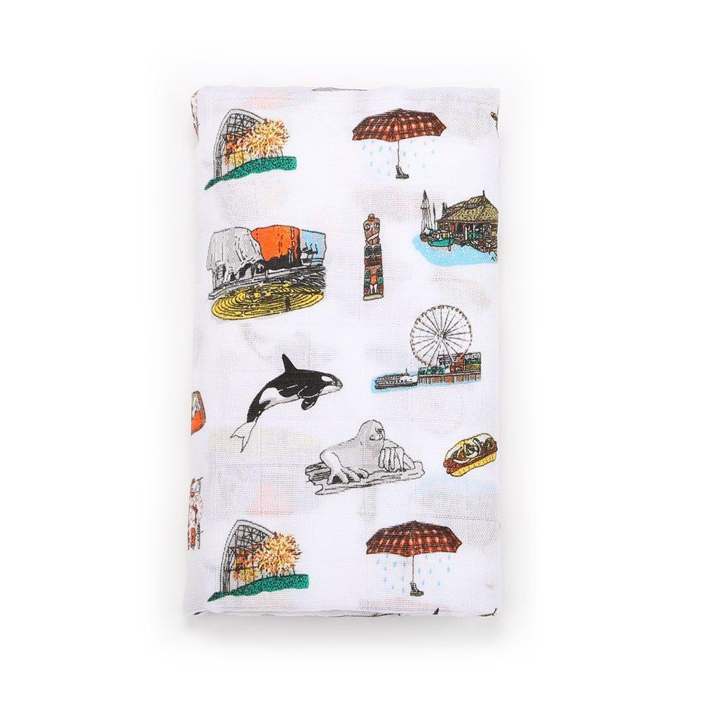 White muslin swaddle blanket with Seattle landmarks like the Space Needle and Pike Place Market, on a white background.