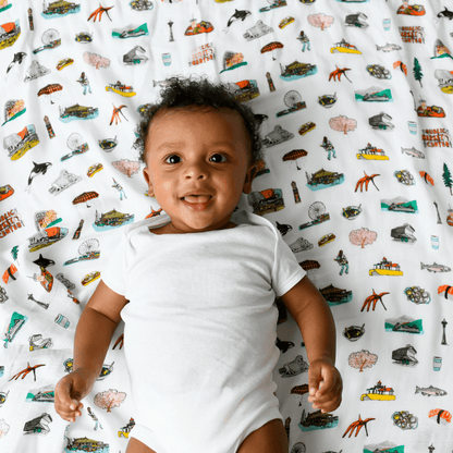 Seattle-themed baby muslin swaddle blanket with iconic landmarks in soft pastel colors, including the Space Needle.
