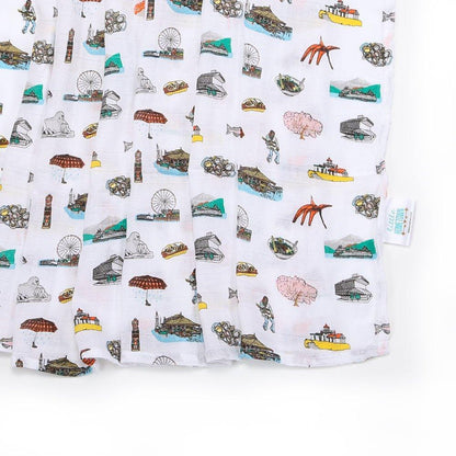 Seattle-themed baby muslin swaddle blanket with iconic landmarks in soft pastel colors on a white background.