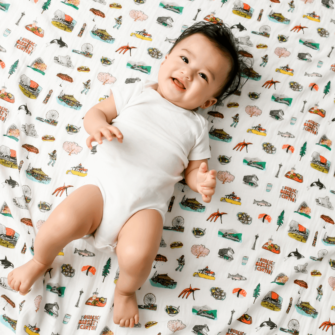 White muslin swaddle blanket with Seattle landmarks like the Space Needle, ferris wheel, and Mount Rainier.