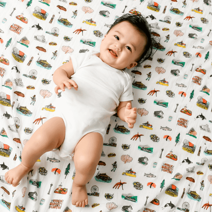 White muslin swaddle blanket with Seattle landmarks like the Space Needle, ferris wheel, and Mount Rainier.