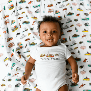 White baby onesie with "Seattle Foodie" text and icons of a coffee cup, fish, and Space Needle.