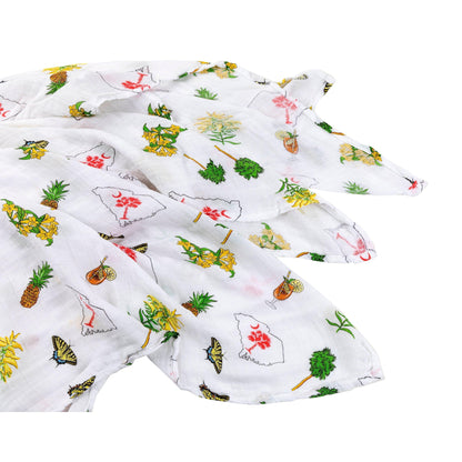 Baby girl swaddled in a white muslin blanket with pink South Carolina motifs, lying on a soft surface.