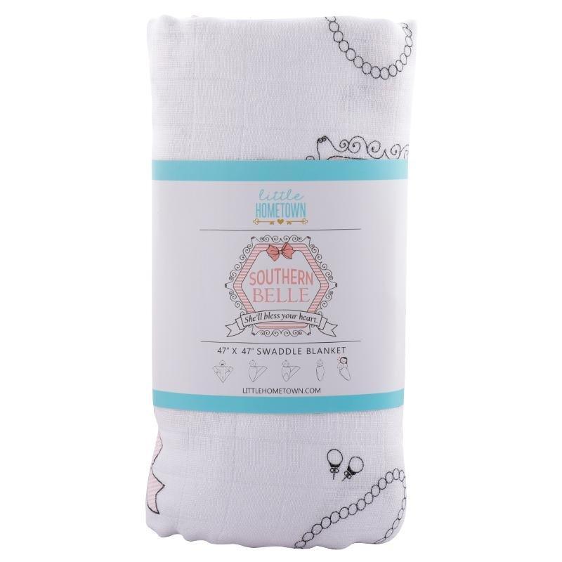 White muslin swaddle blanket with pink magnolia flowers and green leaves, folded neatly on a white background.
