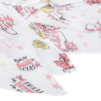 Texas-themed baby girl muslin swaddle blanket with pink accents, featuring state icons and "Texas Baby Girl" text.