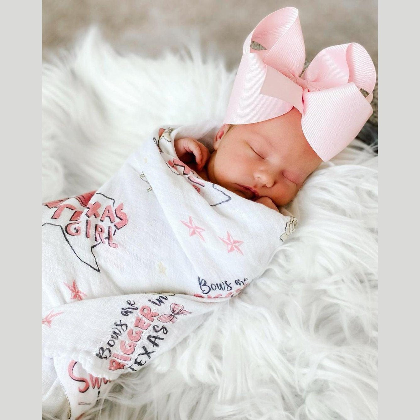 Pink muslin swaddle blanket with "Texas Baby Girl" text and state icons, including a cowboy hat and boots.
