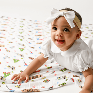 Texas-themed baby muslin swaddle blanket with state icons like cowboy boots, armadillos, and bluebonnets.