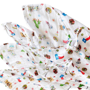White muslin swaddle blanket with Texas-themed illustrations, including cacti, cowboy boots, and state symbols.